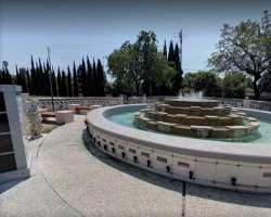 There are waterfall, mature trees, and stone monuments in the cemetery.